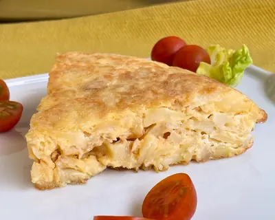 Porción de tortilla de patatas jugosa con tomates cherry